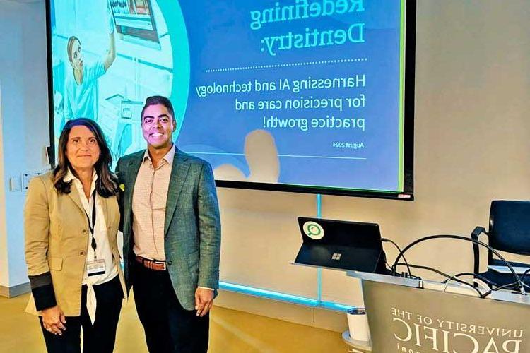 man and woman standing side by side in front of a screen projecting a presentation titled Redefining Dentistry